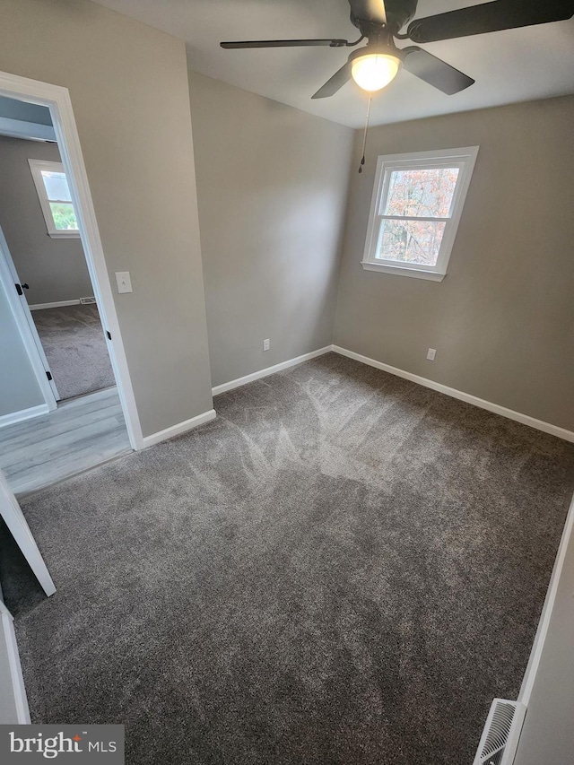 unfurnished bedroom featuring multiple windows, carpet flooring, and baseboards