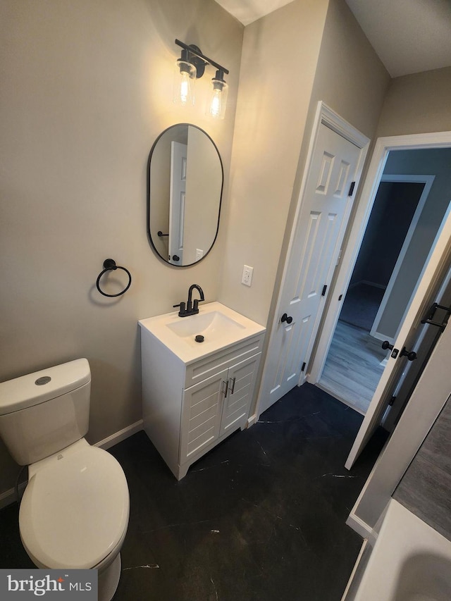 bathroom featuring baseboards, toilet, and vanity