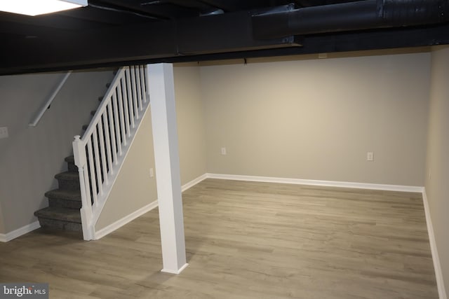 finished below grade area featuring stairway, baseboards, and light wood-style flooring