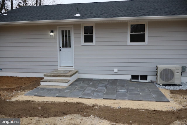 entrance to property featuring ac unit and a shingled roof