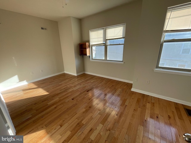 unfurnished room featuring visible vents, baseboards, and hardwood / wood-style flooring