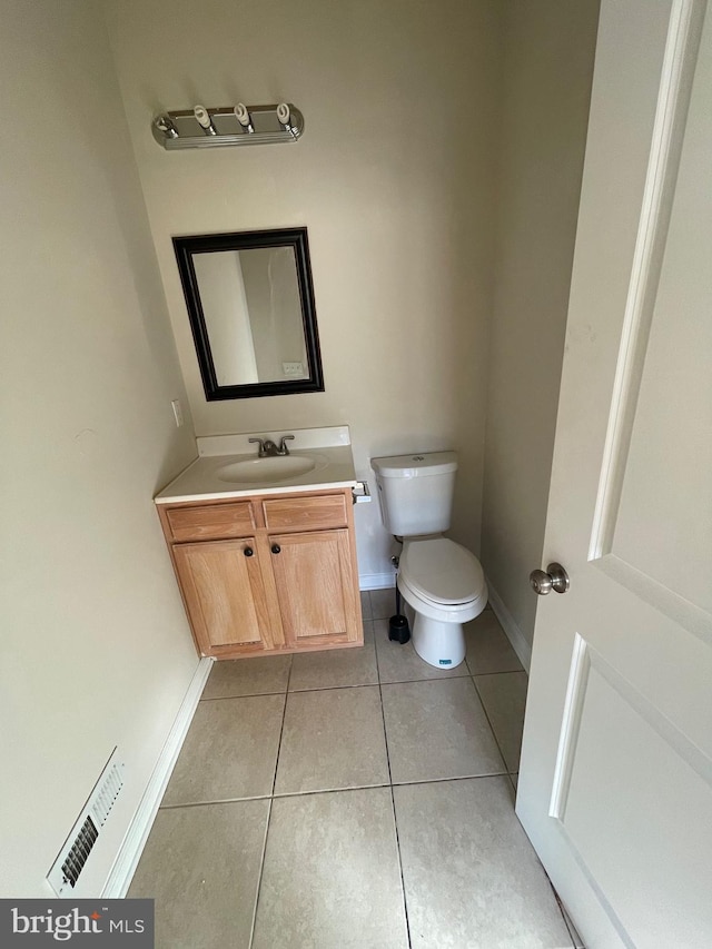 half bath with visible vents, toilet, vanity, and tile patterned flooring