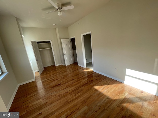 unfurnished bedroom featuring a ceiling fan, wood finished floors, baseboards, and a closet