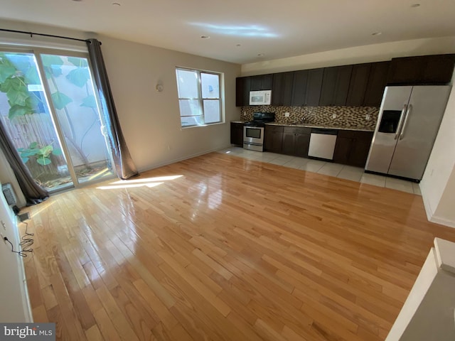 kitchen with light wood-type flooring, stainless steel appliances, baseboards, and decorative backsplash