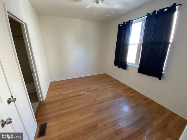 spare room with visible vents, a ceiling fan, light wood-type flooring, and baseboards