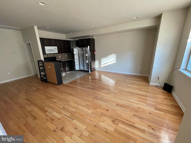 kitchen featuring tasteful backsplash, light wood finished floors, open floor plan, a breakfast bar, and stainless steel appliances