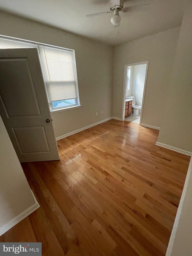 unfurnished bedroom featuring connected bathroom, a ceiling fan, light wood-type flooring, and baseboards