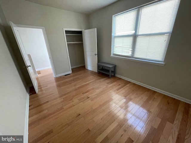 unfurnished bedroom featuring baseboards, a closet, and light wood finished floors