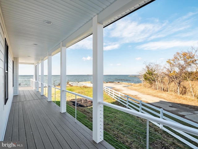 wooden terrace with a view of the beach, a lawn, and a water view