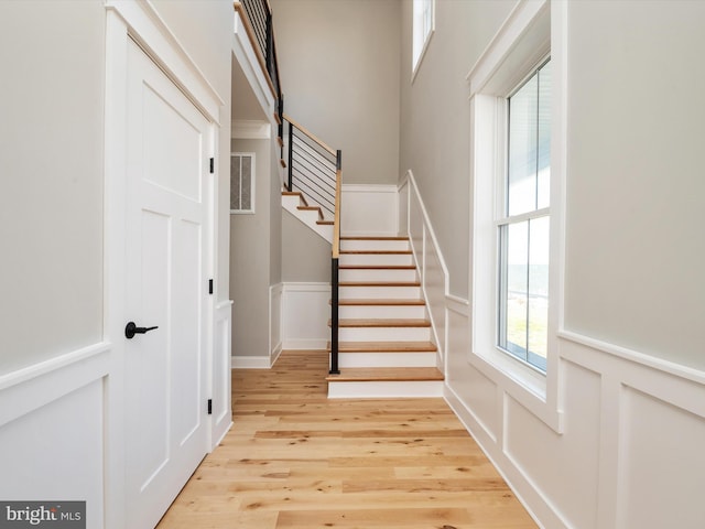 stairs with visible vents, wood finished floors, wainscoting, and a decorative wall