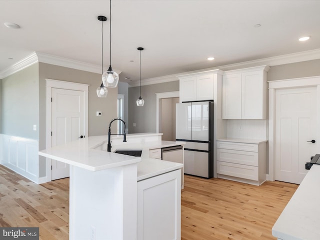 kitchen featuring freestanding refrigerator, a sink, light countertops, white cabinets, and light wood-style floors