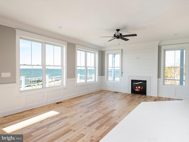 living room with light wood finished floors, visible vents, ornamental molding, a fireplace, and a decorative wall