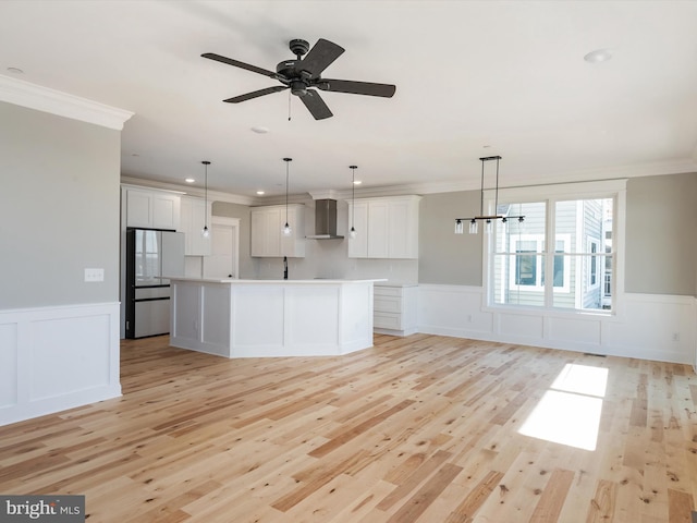 kitchen with wall chimney exhaust hood, freestanding refrigerator, and ornamental molding