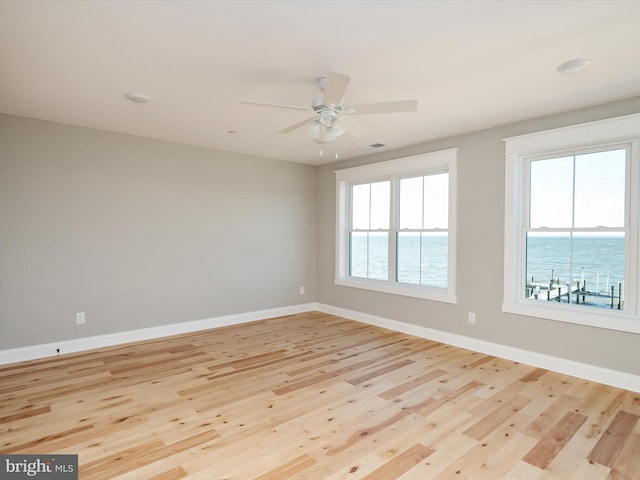 spare room with baseboards, light wood-style flooring, and a ceiling fan