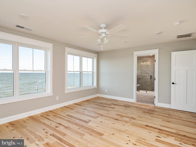 empty room featuring visible vents, ceiling fan, baseboards, and wood finished floors