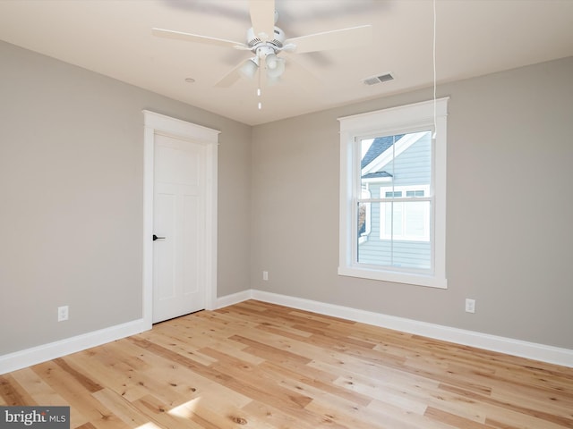 unfurnished room with visible vents, wood finished floors, baseboards, and ceiling fan