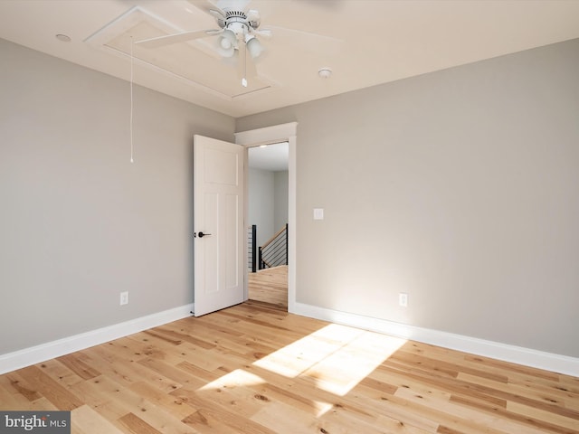 empty room featuring attic access, baseboards, and light wood finished floors