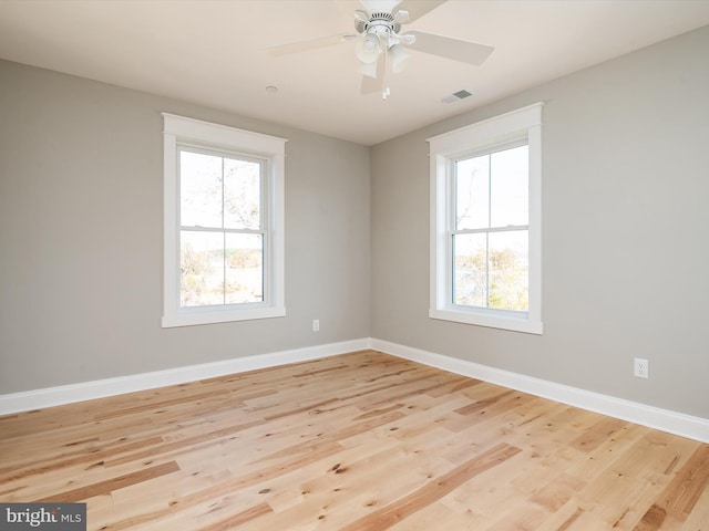 empty room featuring light wood finished floors, visible vents, and plenty of natural light