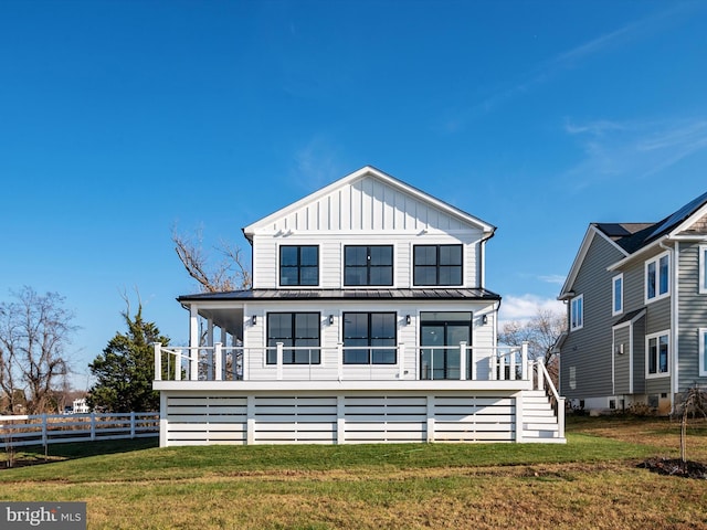 view of front facade with board and batten siding, a front lawn, a standing seam roof, and fence