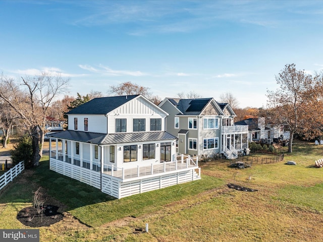 back of property with board and batten siding, fence, a lawn, metal roof, and a standing seam roof