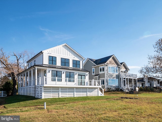 back of property with fence, a standing seam roof, a lawn, board and batten siding, and metal roof