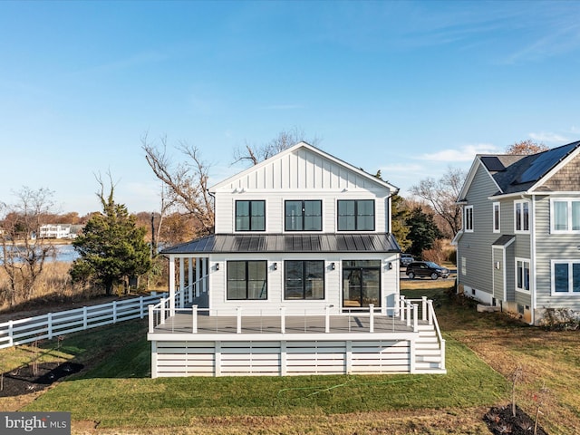 rear view of house featuring board and batten siding, a wooden deck, a yard, and fence