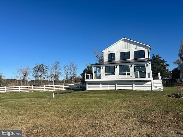 view of front of home featuring board and batten siding, a front lawn, and fence