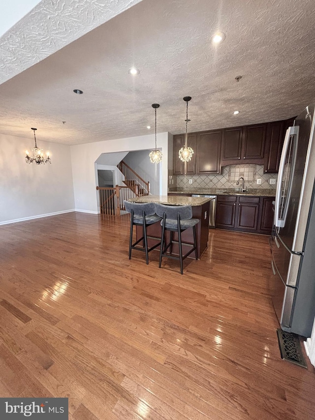 kitchen featuring a chandelier, decorative backsplash, freestanding refrigerator, and wood-type flooring