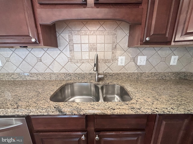 kitchen with light stone counters, backsplash, and a sink