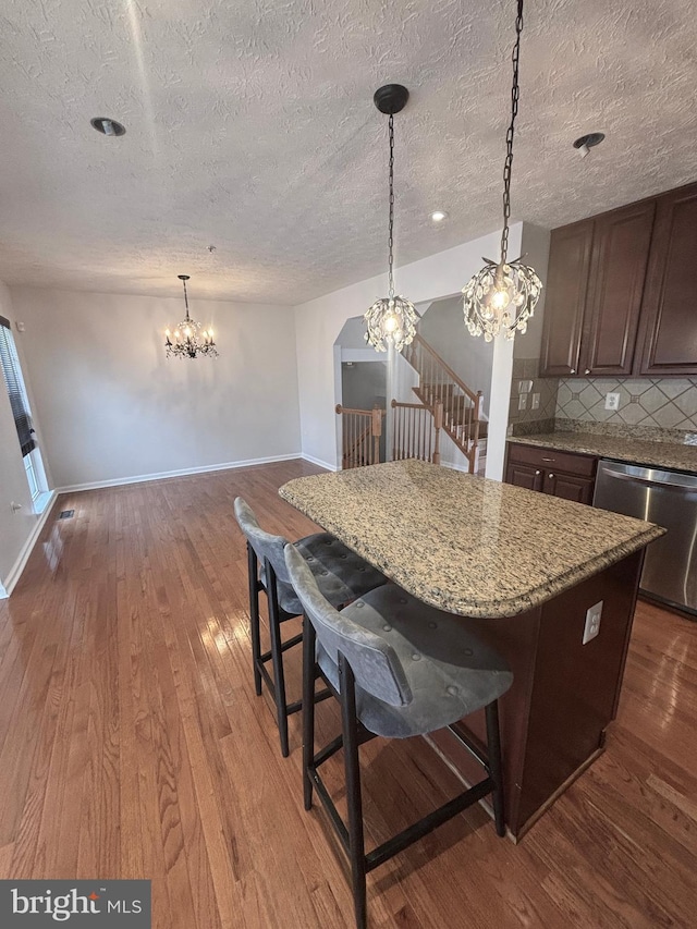 kitchen with baseboards, dark wood-type flooring, dishwasher, tasteful backsplash, and a center island