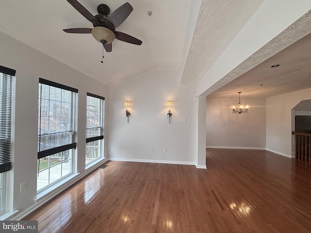 unfurnished room with ceiling fan with notable chandelier, a textured ceiling, hardwood / wood-style floors, baseboards, and vaulted ceiling