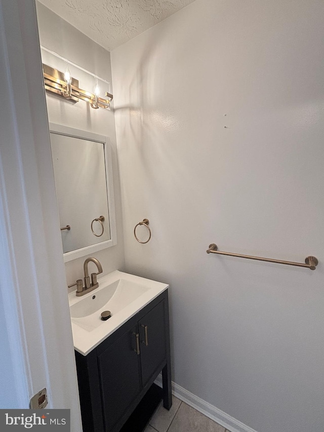 bathroom with tile patterned flooring, a textured ceiling, vanity, and baseboards