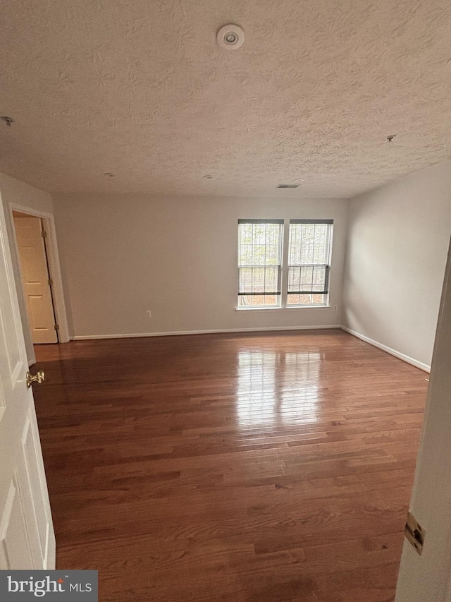 unfurnished room featuring baseboards, a textured ceiling, and wood finished floors