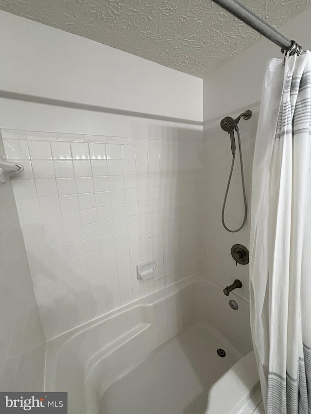 full bath featuring a textured ceiling and shower / bath combo with shower curtain