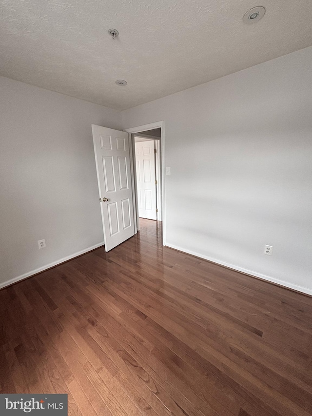 empty room with baseboards and wood finished floors