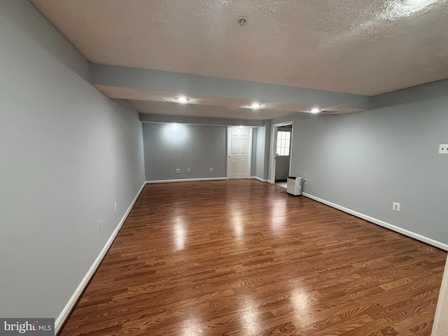 interior space featuring a textured ceiling, baseboards, and wood finished floors