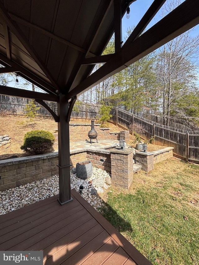 wooden deck featuring a lawn, a fenced backyard, and an outdoor fire pit