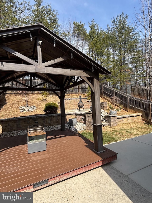 wooden terrace featuring a gazebo and fence