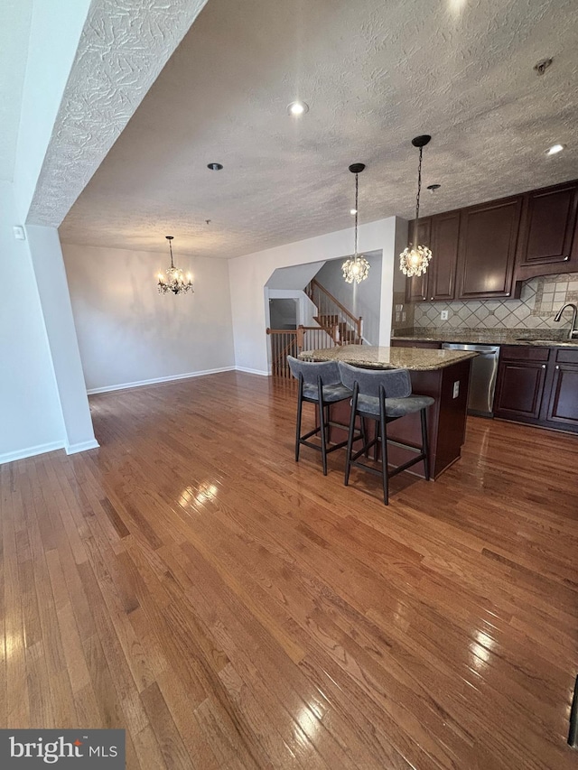 kitchen with decorative backsplash, dishwasher, a chandelier, and dark wood finished floors