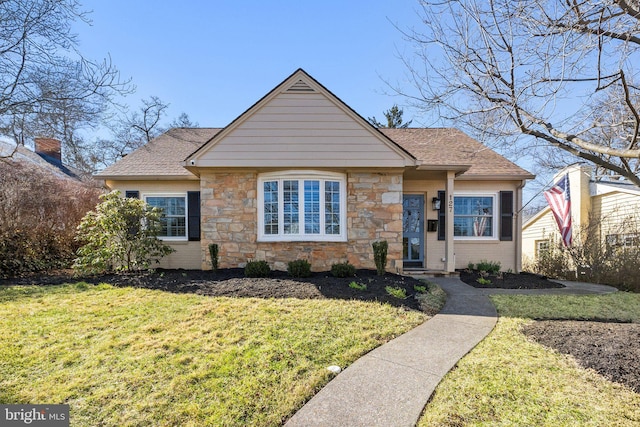 view of front facade featuring stone siding, brick siding, roof with shingles, and a front yard