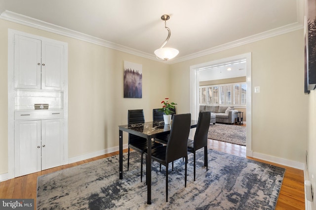 dining area featuring crown molding, wood finished floors, and baseboards