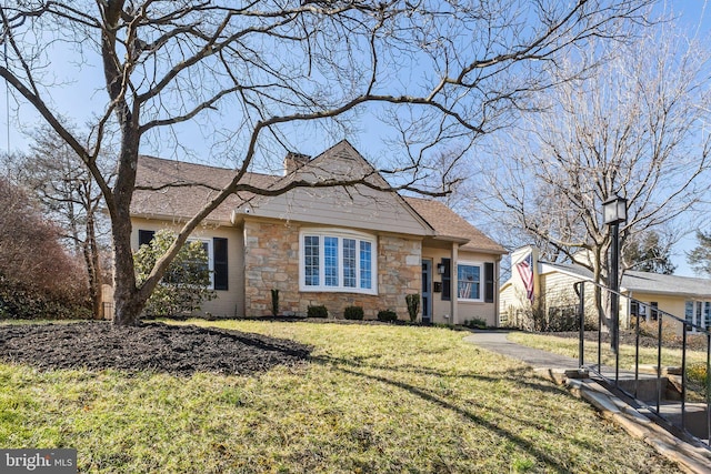 view of front of home with stone siding, a chimney, a front yard, and a shingled roof