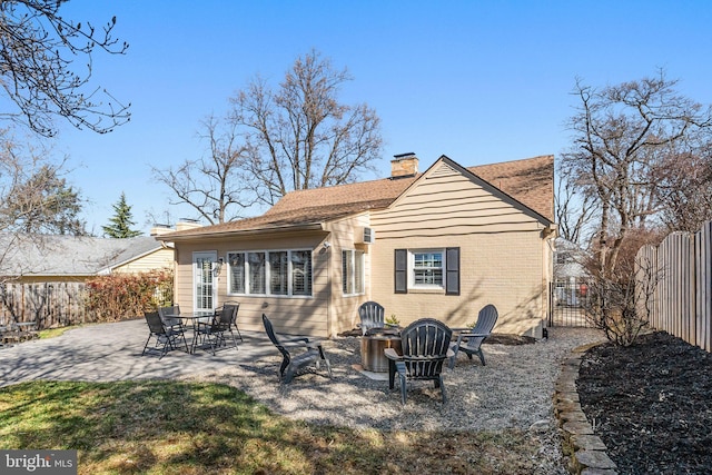 rear view of property with a patio, a fenced backyard, a shingled roof, a chimney, and brick siding