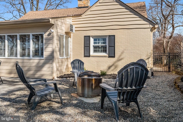 rear view of property featuring fence, a shingled roof, brick siding, a chimney, and a patio area