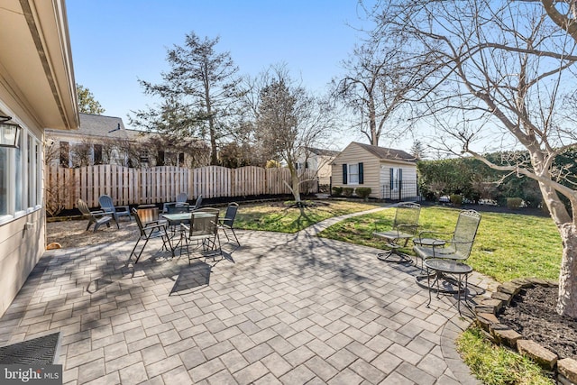 view of patio / terrace with an outbuilding, outdoor dining space, and fence