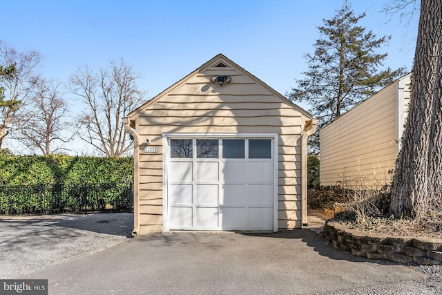 detached garage featuring driveway and fence