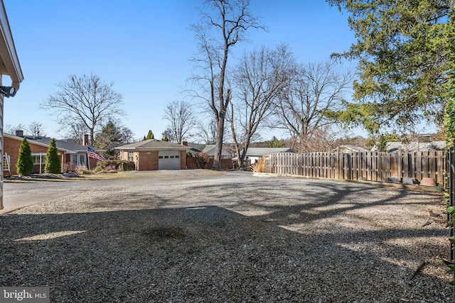 view of yard featuring an attached garage, fence, a residential view, and driveway