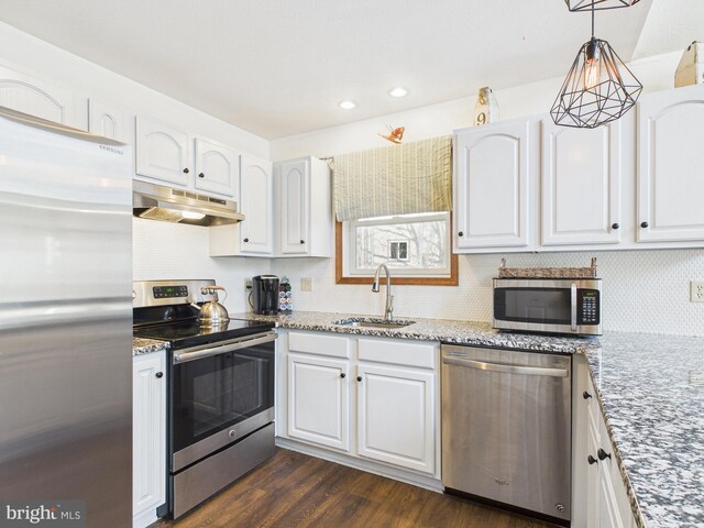 kitchen with under cabinet range hood, appliances with stainless steel finishes, dark wood-style floors, white cabinets, and a sink