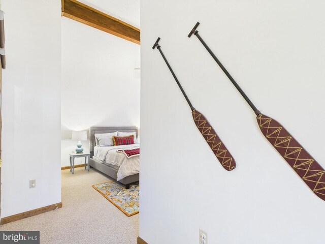 carpeted bedroom featuring beam ceiling and baseboards