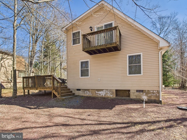 rear view of property featuring a wooden deck and crawl space